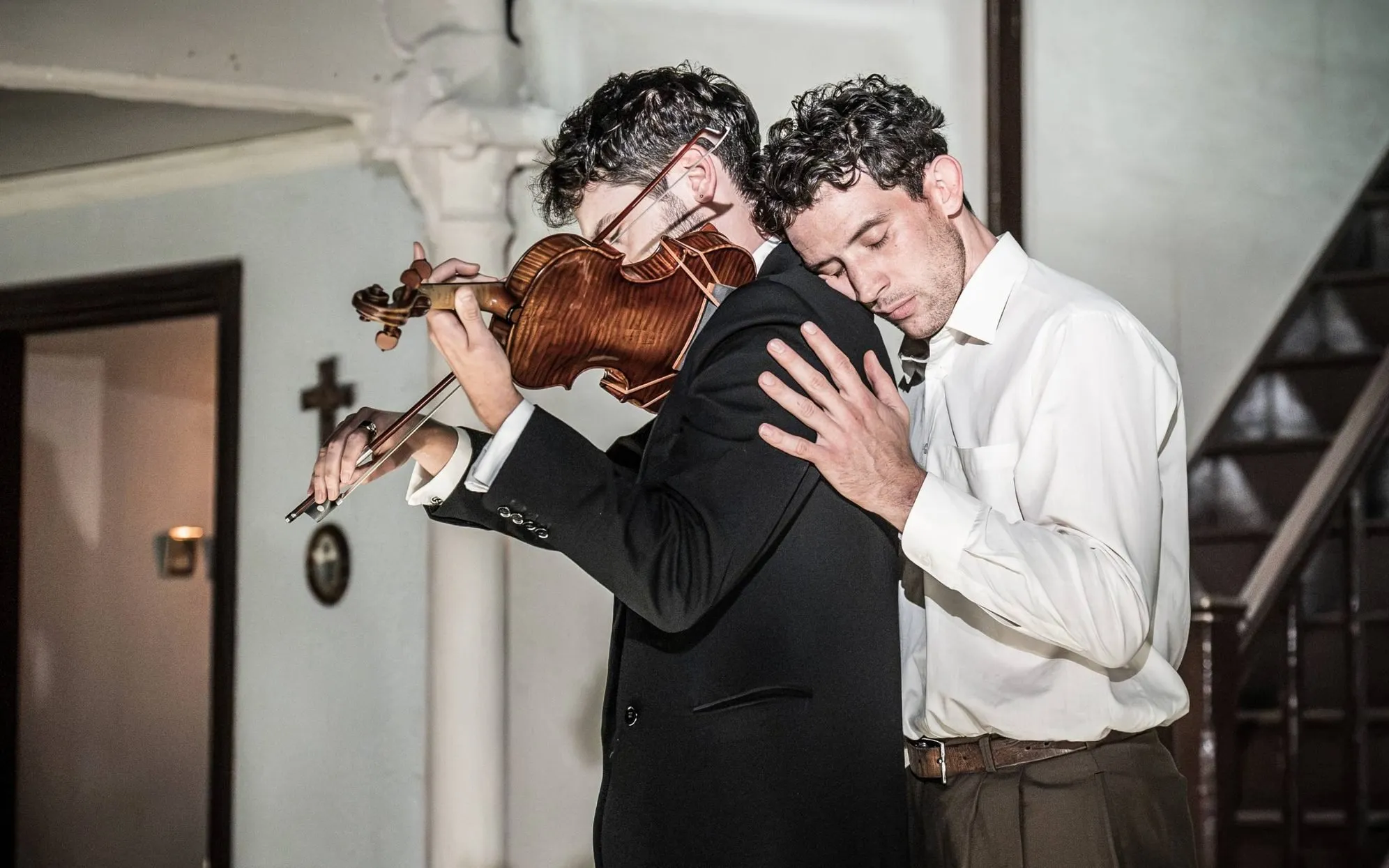 Two men embrace as one plays the violin, Golden Boy at the Almeida Theatre